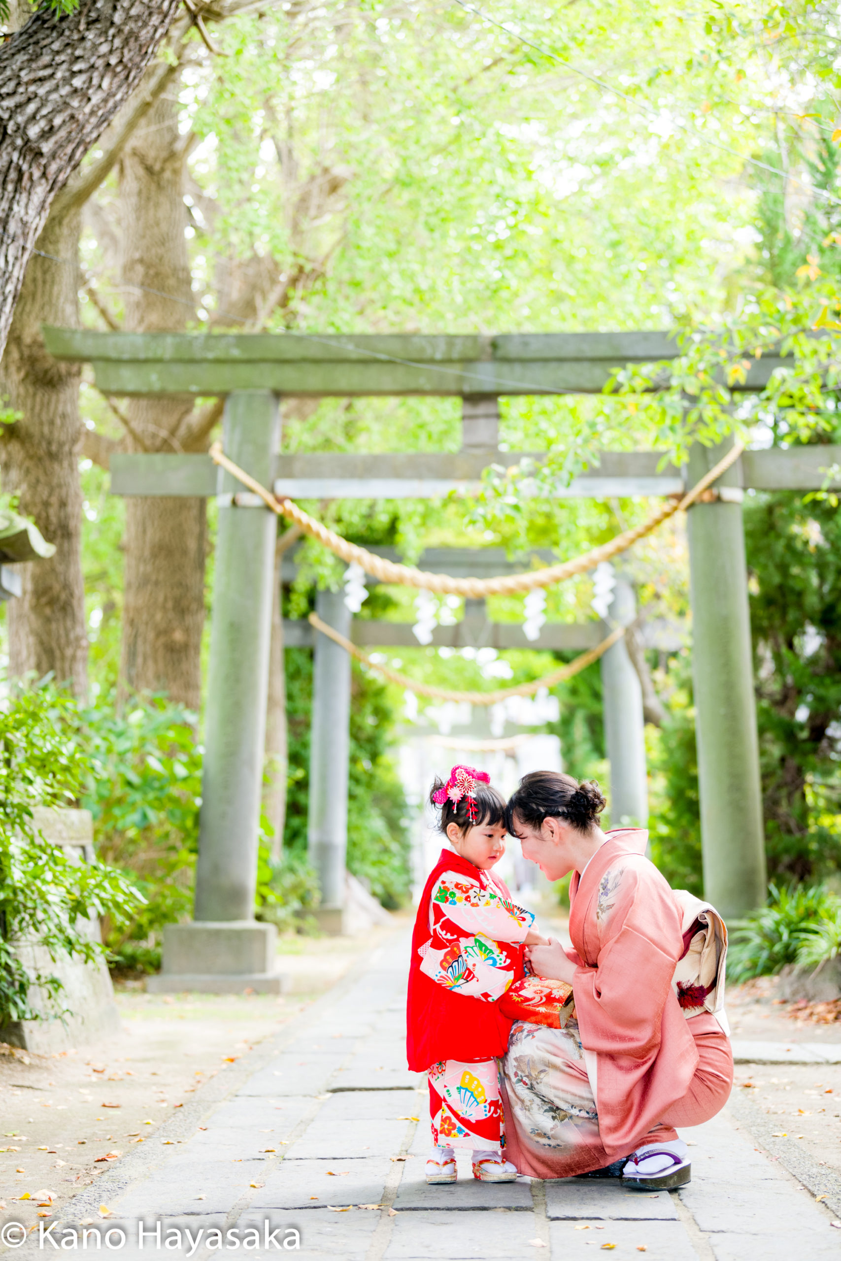 鳥居の前で七五三のお参りをする親子