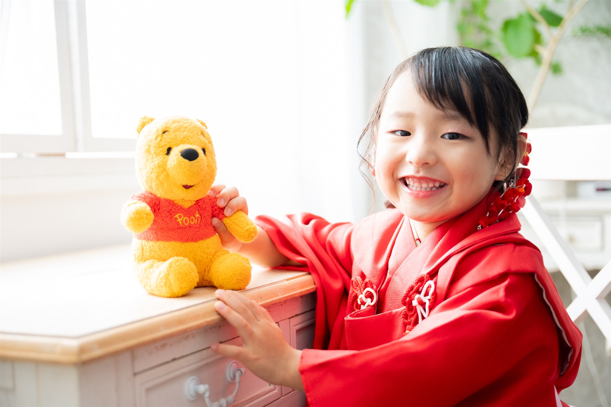 スタジオでぬいぐるみと一緒に笑う七五三の女の子