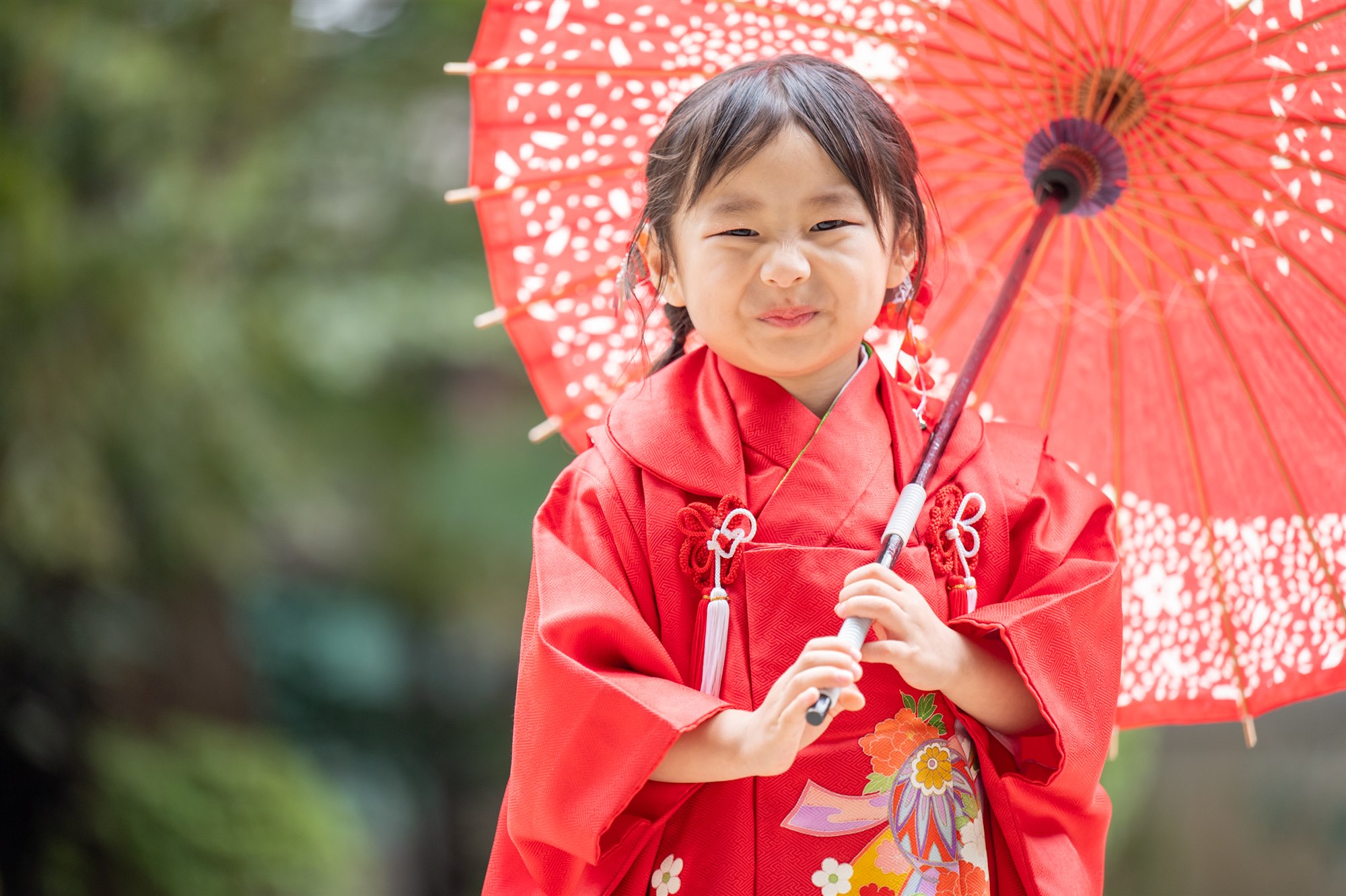久伊豆神社で赤い和傘を持ってにっこり笑う七五三の女の子