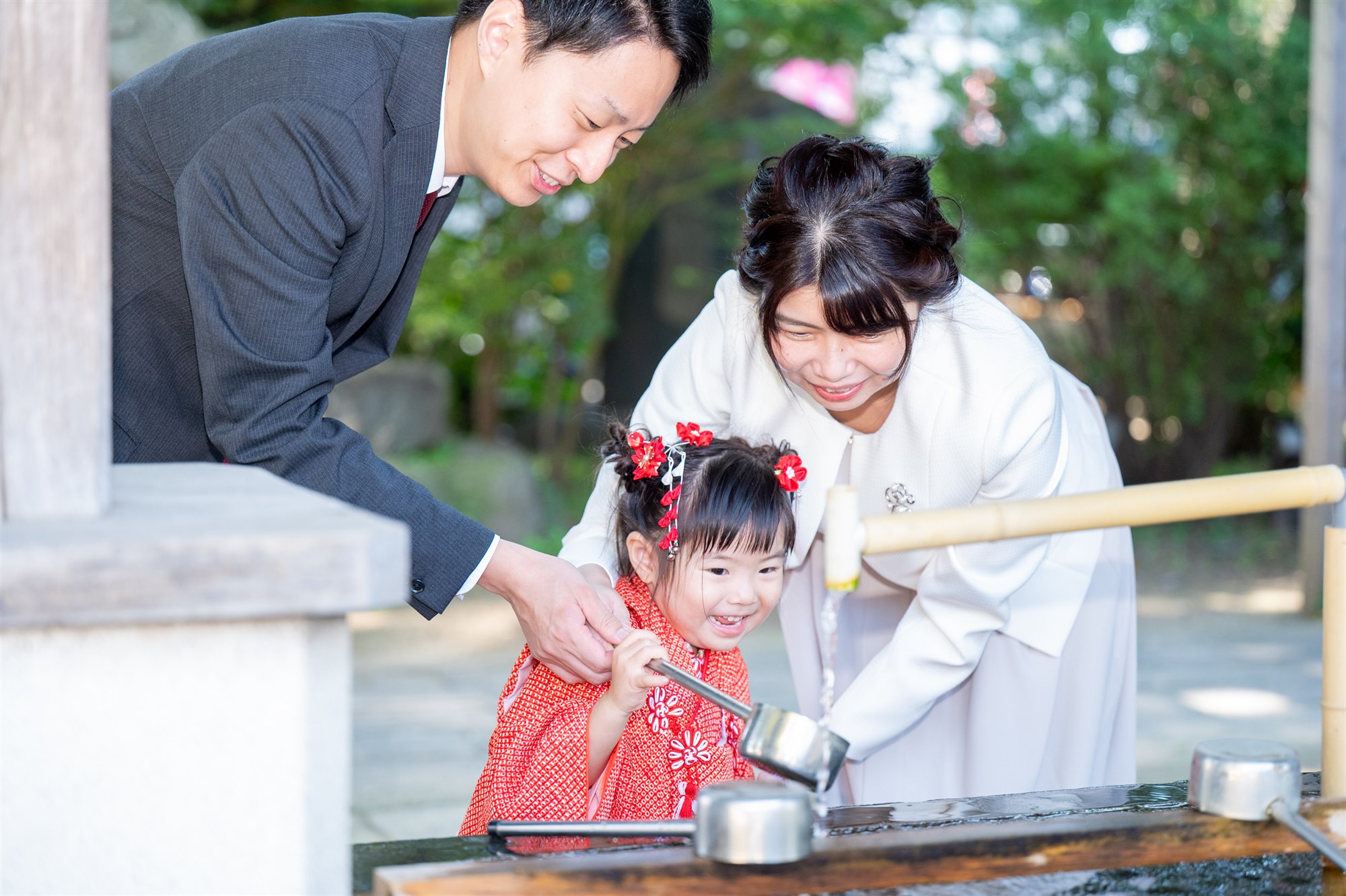 手水舎でパパとママに見守られて手を清める七五三の女の子