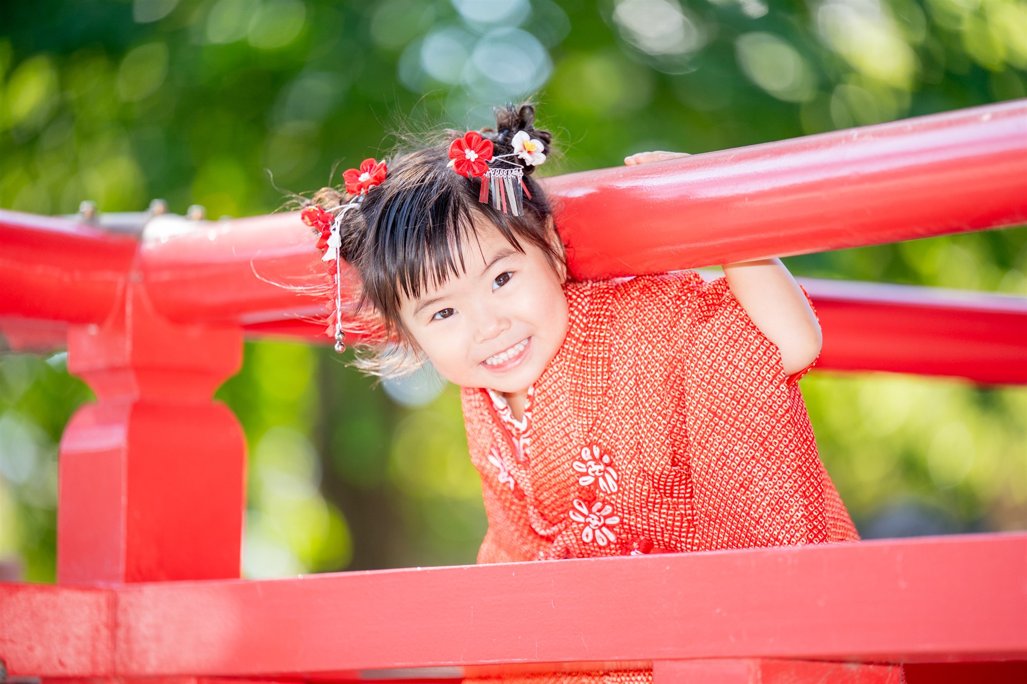 赤い橋の欄干からのぞく3歳の七五三の女の子