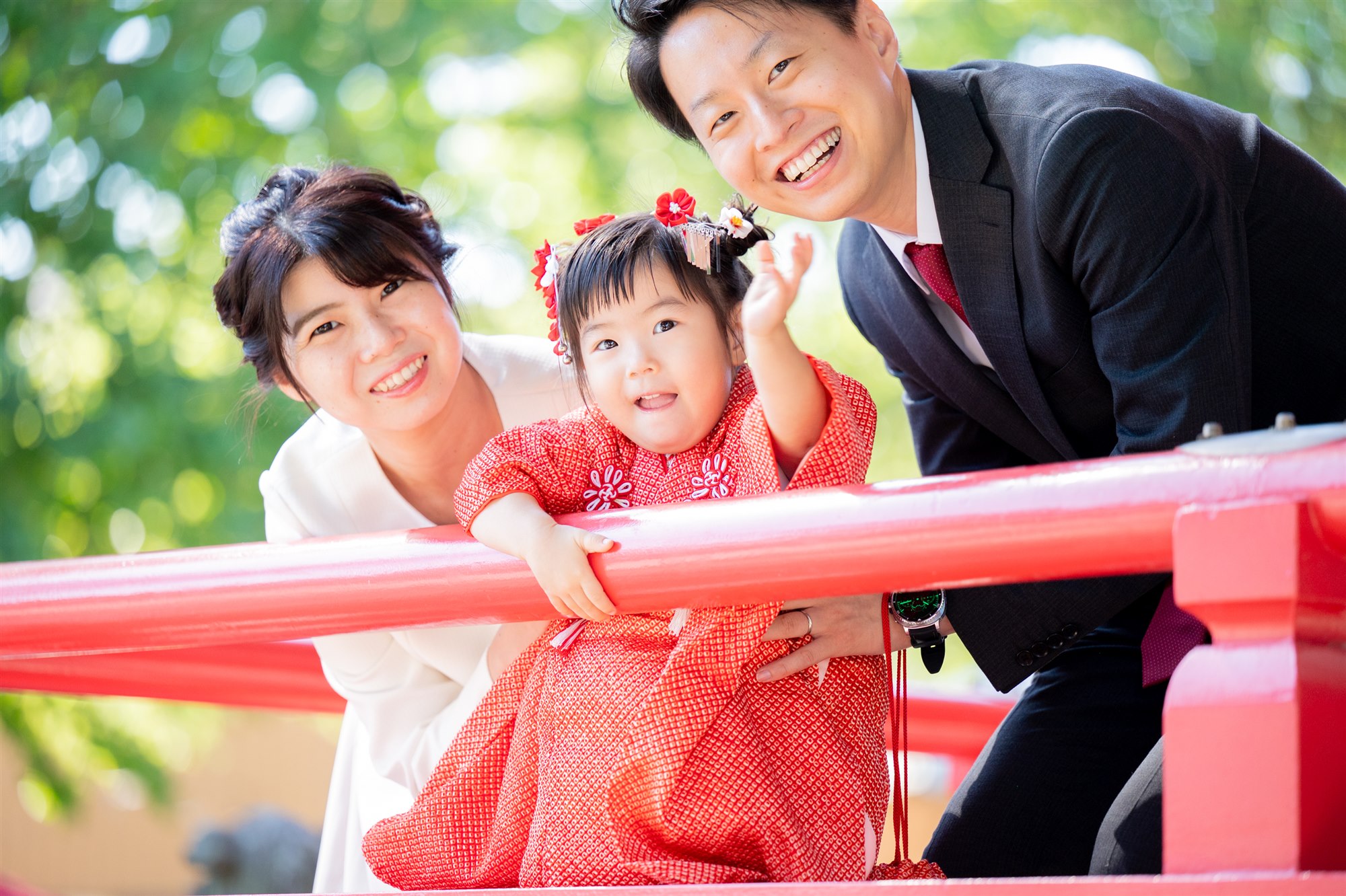 赤い橋でパパとママに見守られる七五三の女の子