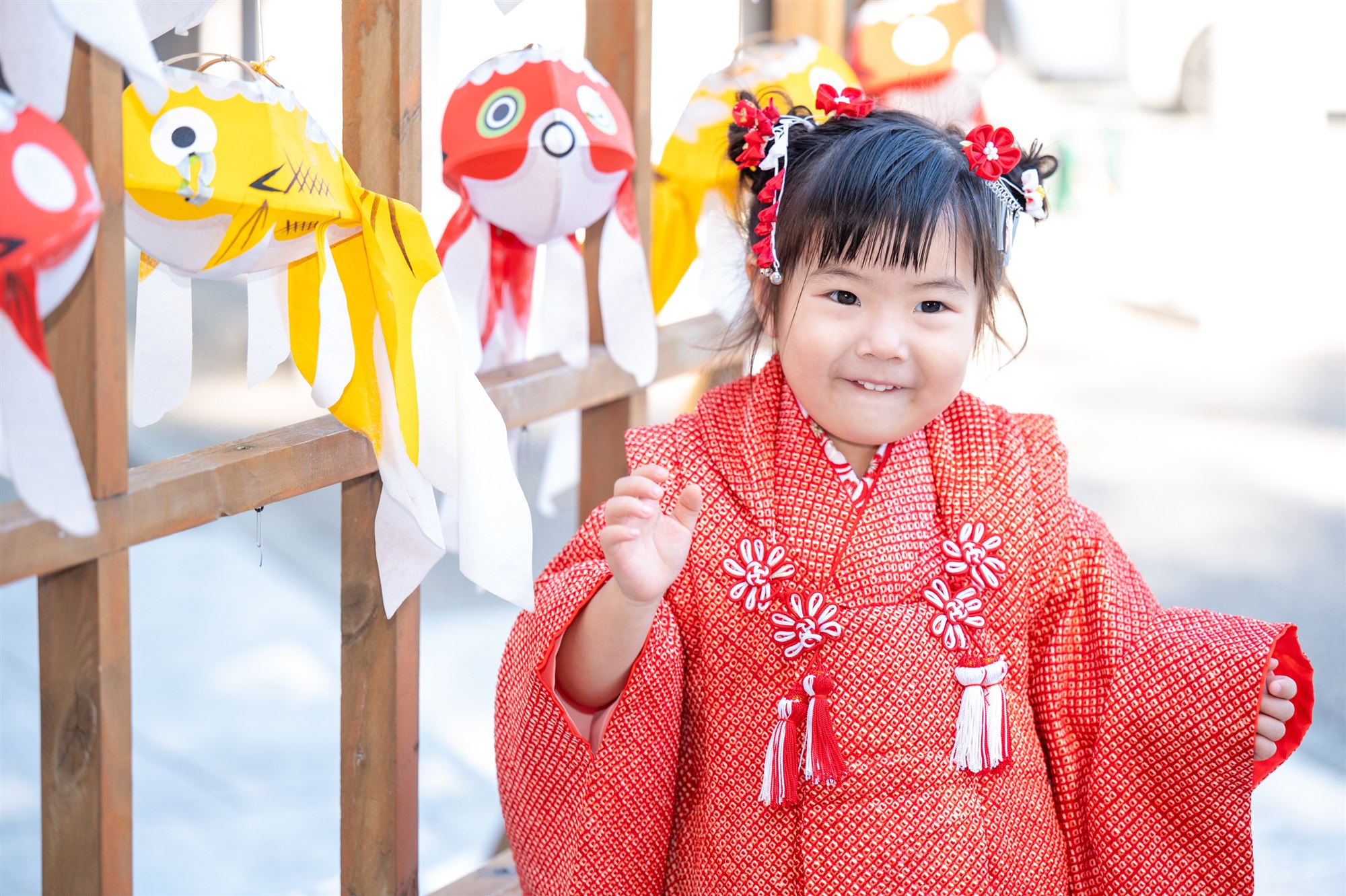 金魚の飾りの前で笑う七五三の女の子