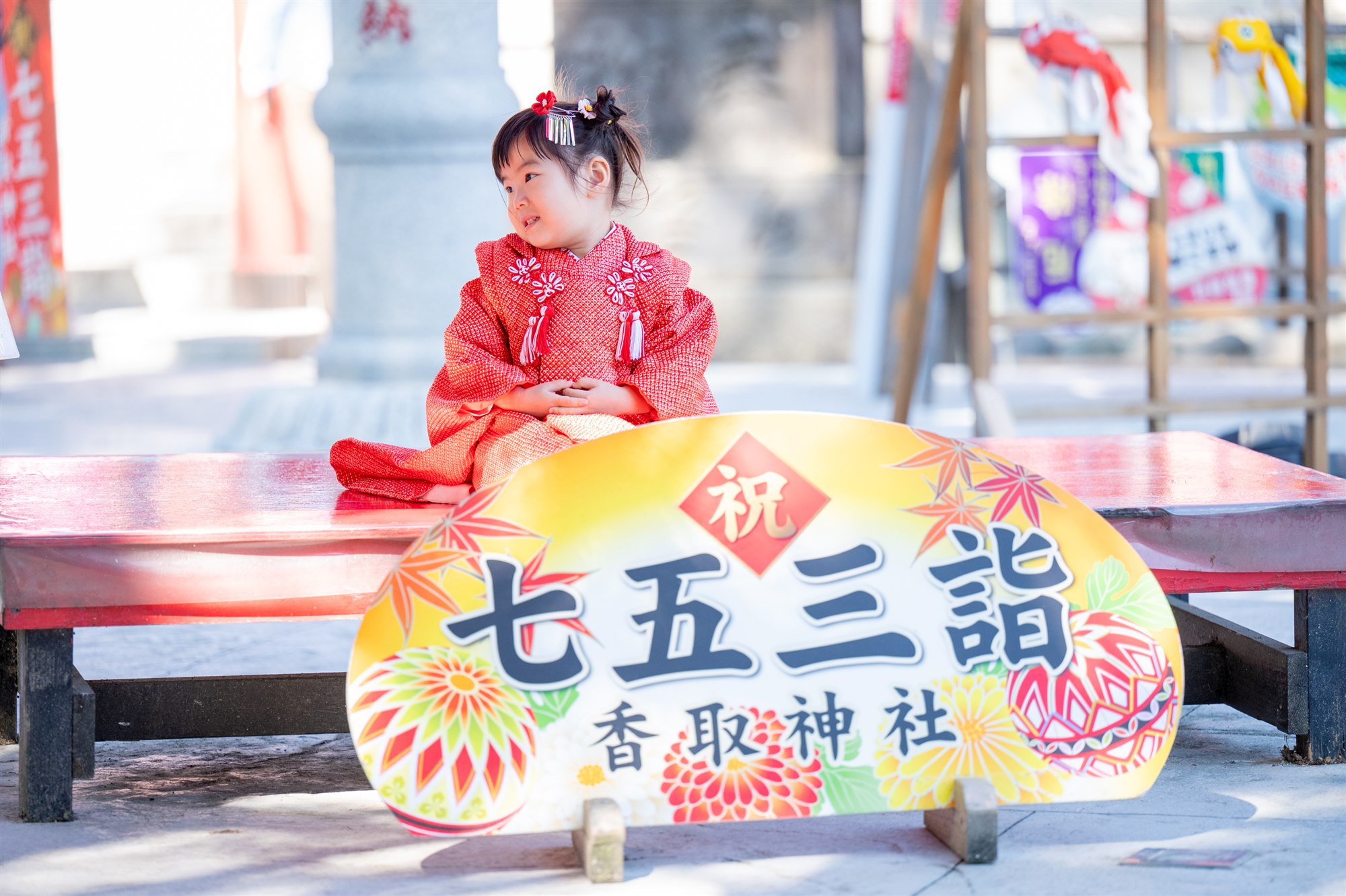 香取神社の七五三詣の看板の前に座る女の子