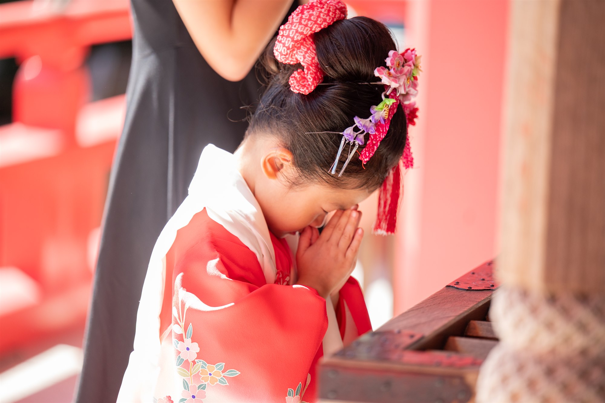 香取神社で手を合わせてお参りをする七五三の女の子