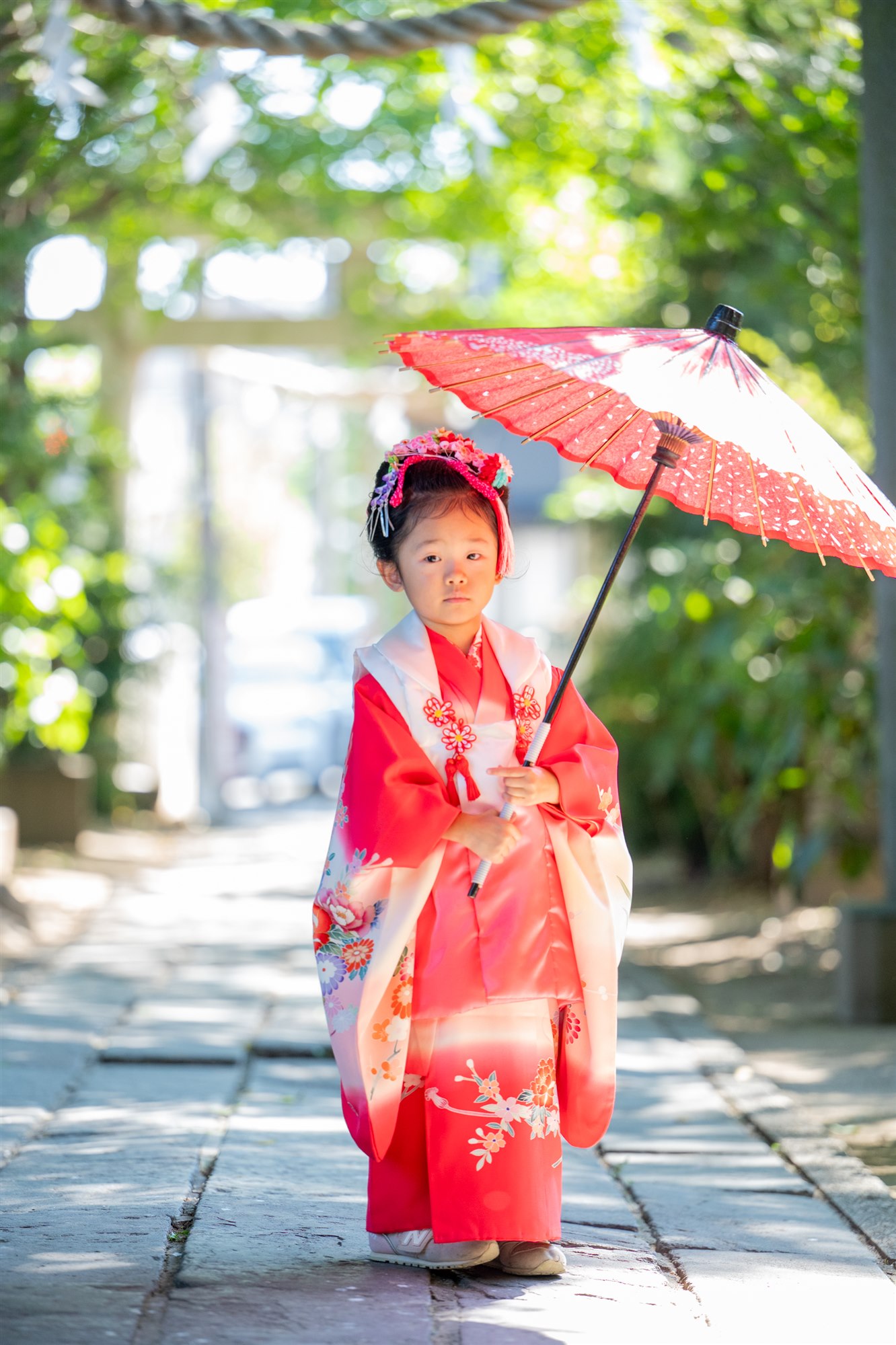鳥居の参道で和傘をさして立つ七五三の女の子