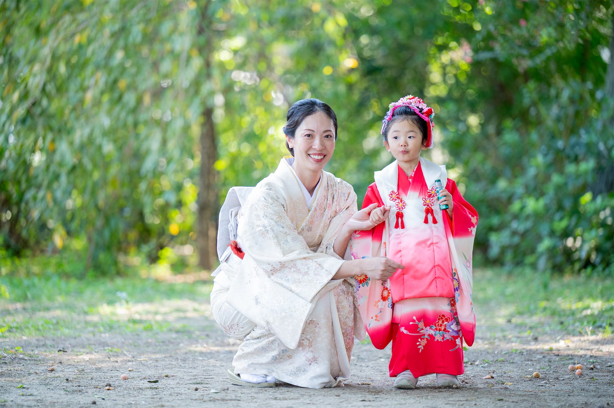 香取神社の境内でしゃがんで七五三の娘と向き合うお着物のママ
