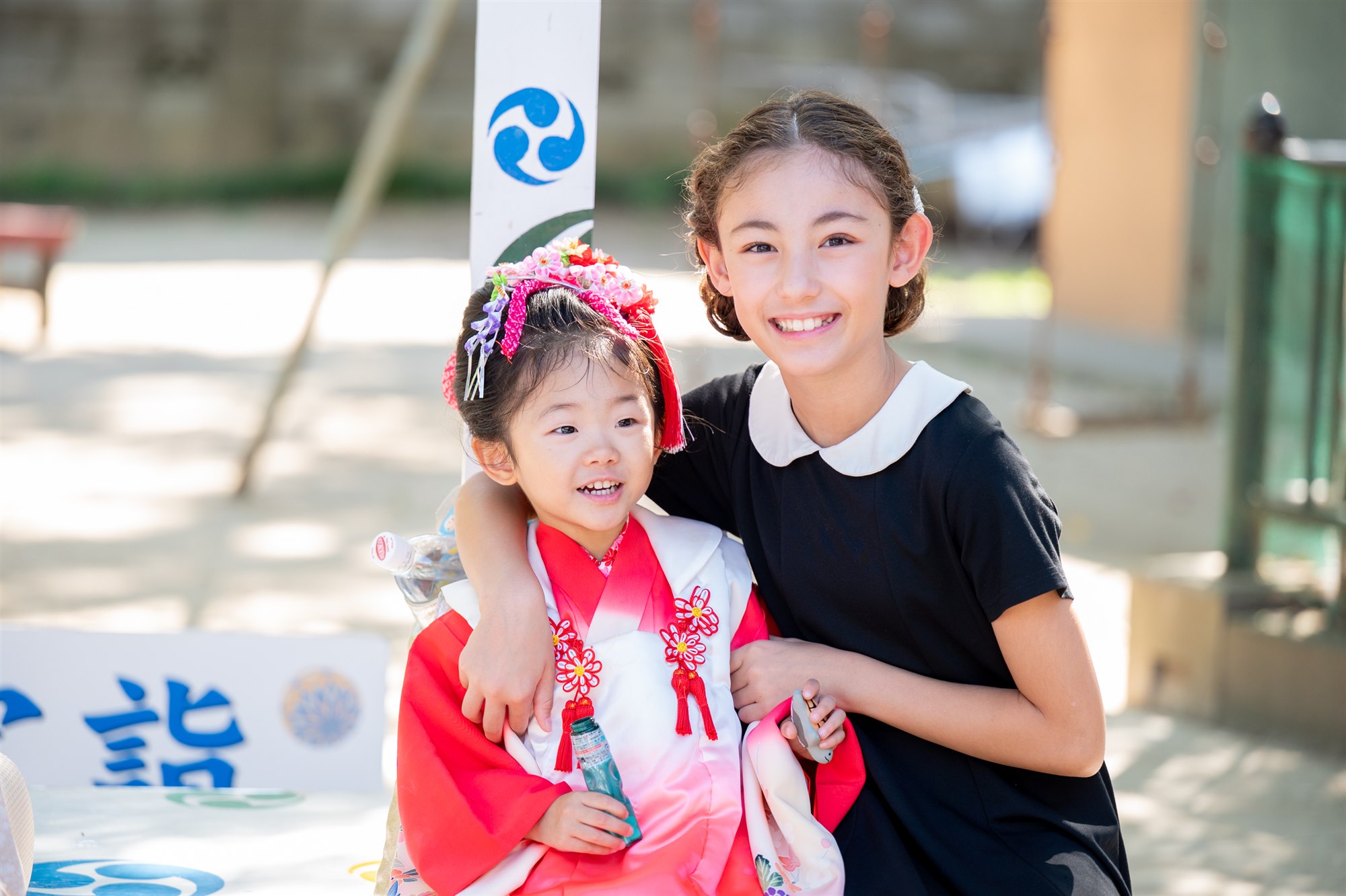 お姉ちゃんに寄り添われて笑う七五三の姉妹