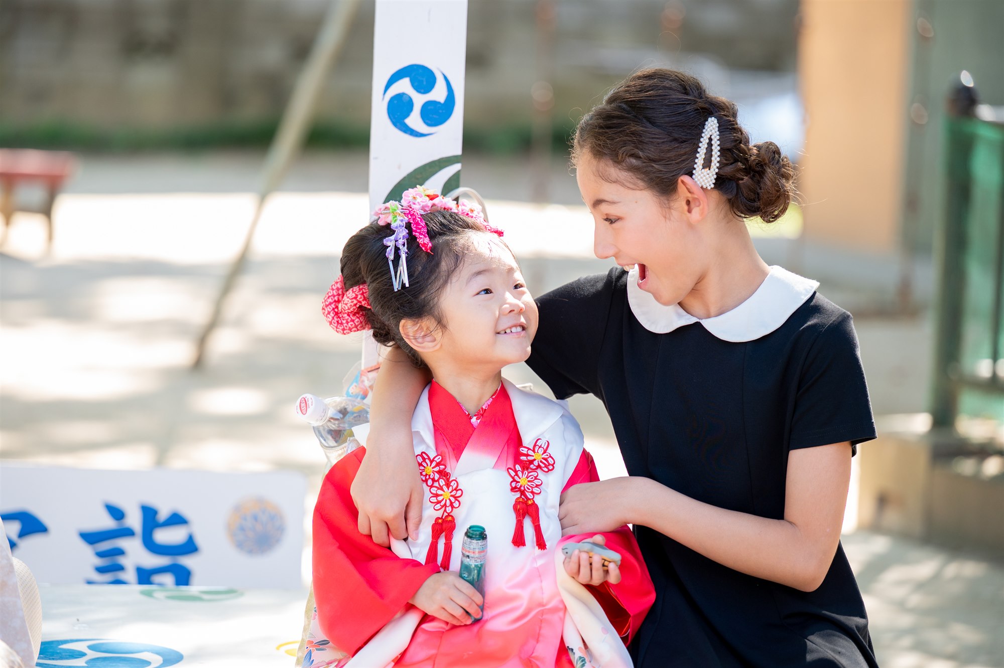 お姉ちゃんの顔を見てにっこり笑う3歳の七五三の妹ちゃん
