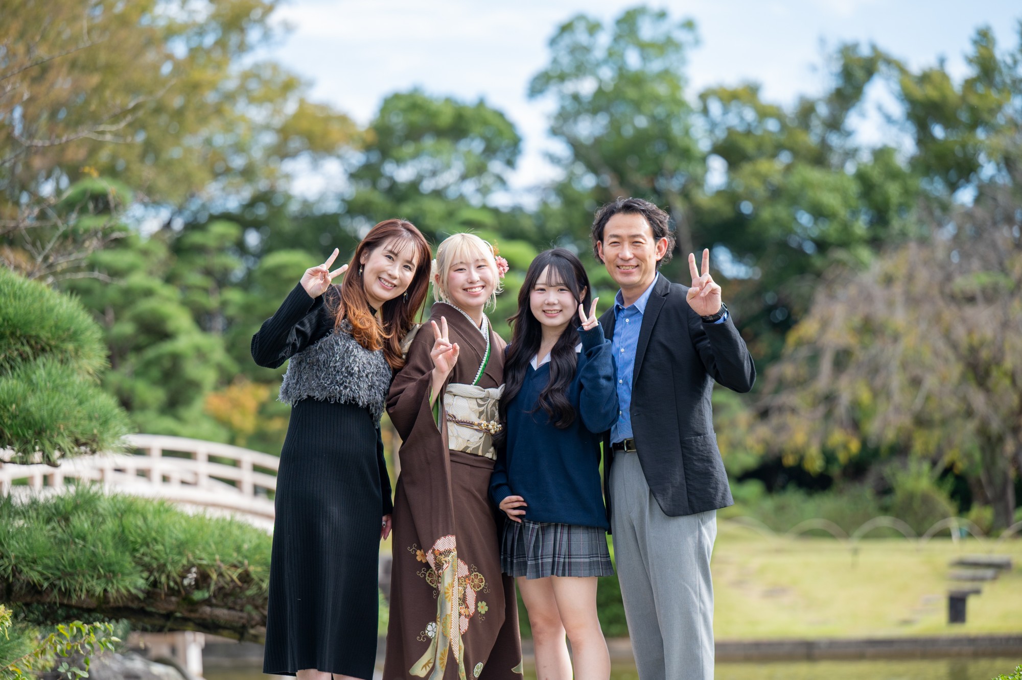 花田苑の日本庭園で、成人式の振袖姿の娘さんとママ、妹さん、パパが笑顔でピースをするご家族写真