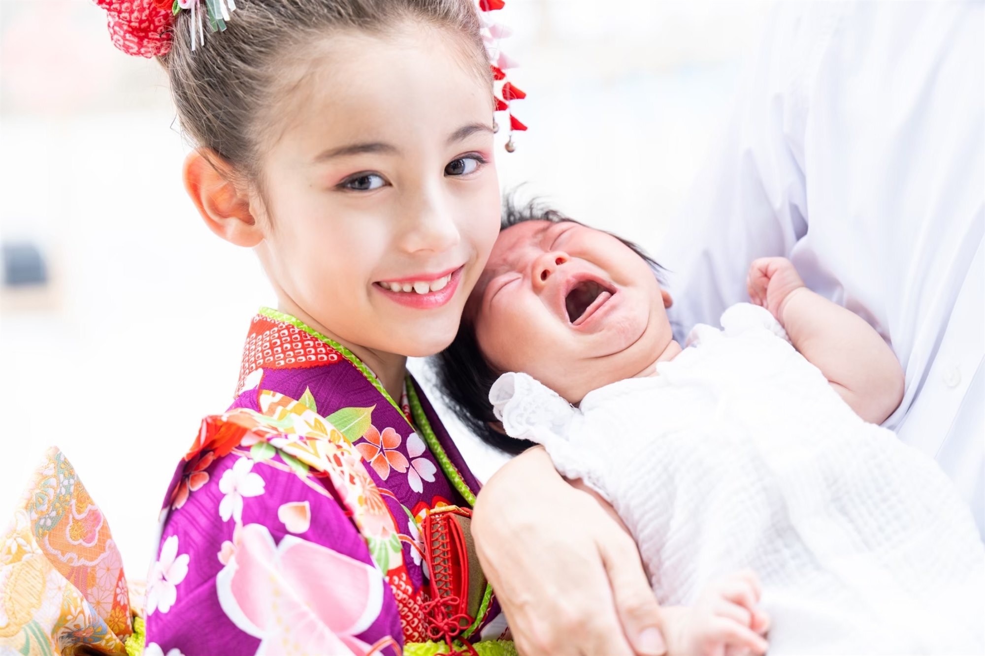 赤ちゃんの妹を抱っこして笑う7歳の七五三のお姉ちゃん