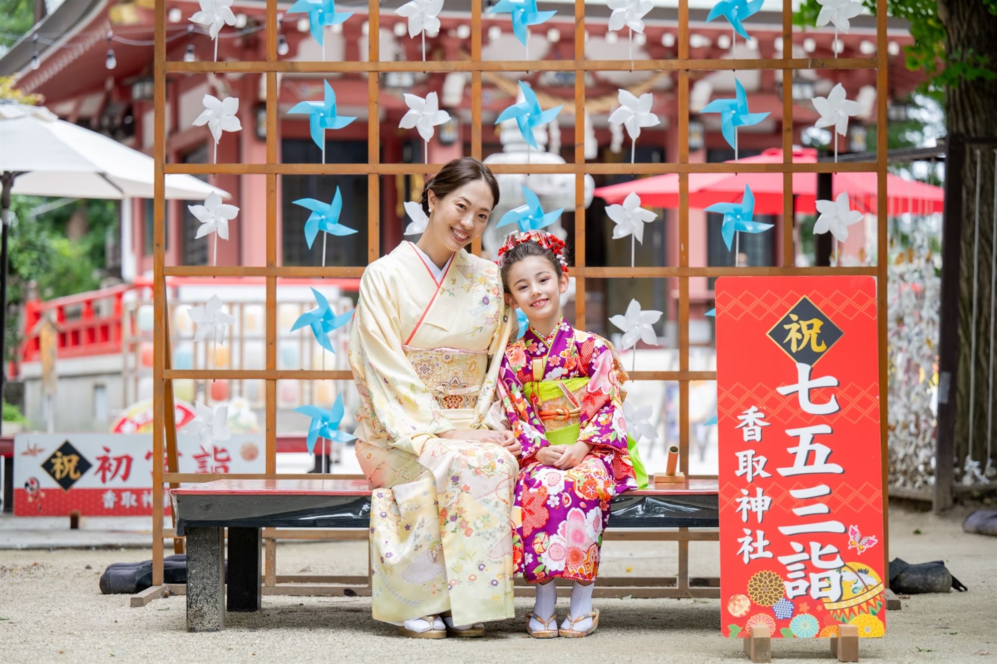 香取神社の七五三詣の看板の前でママと並ぶ7歳の女の子